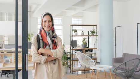 Portrait-of-happy-biracial-businesswoman-walking-with-arms-crossed-in-office-in-slow-motion