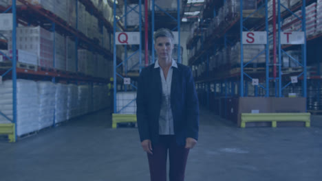 Animation-of-network-of-connections-with-icons-over-caucasian-businesswoman-working-in-warehouse