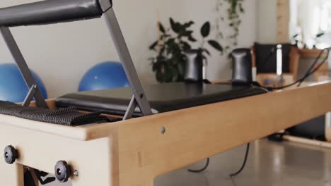 Close-up-of-empty-pilates-rehabilitation-room-with-reformer-and-exercise-balls,-slow-motion