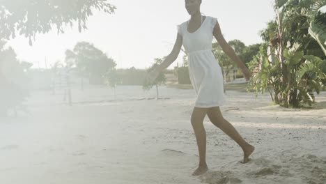Happy-biracial-woman-in-sundress-dancing-on-sunny-beach,-slow-motion