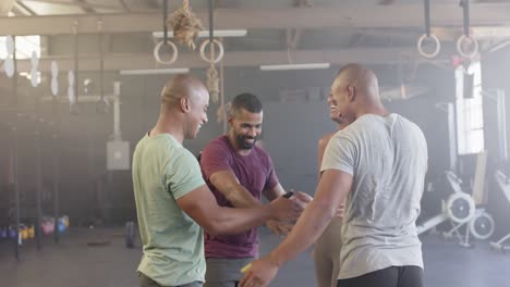 Diverse-group-smiling-and-stacking-hands-after-training-in-fitness-class-at-gym,-in-slow-motion
