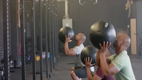 Diverse-male-group-fitness-class-training-at-gym-lifting-and-throwing-medicine-balls,-in-slow-motion