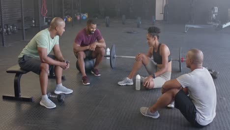 Happy-diverse-group-sitting-and-talking-after-training-in-fitness-class-at-gym,-in-slow-motion