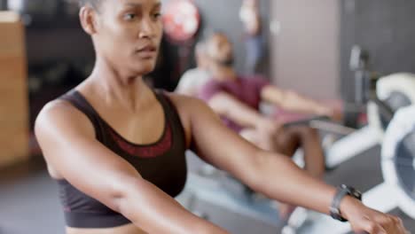 Focused-african-american-woman-training-on-rowing-machine-at-gym,-in-slow-motion