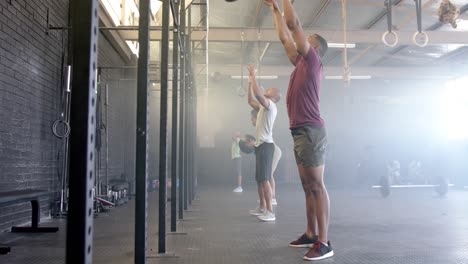Diverse-group-fitness-class-training-at-gym-lifting-and-throwing-medicine-balls,-in-slow-motion