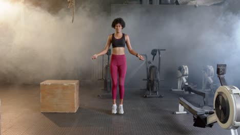 Happy-fit-african-american-woman-jumping-with-skipping-rope,-cross-training-at-gym,-in-slow-motion