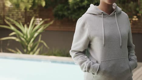 Midsection-of-biracial-woman-wearing-grey-hoodie-with-copy-space-in-garden
