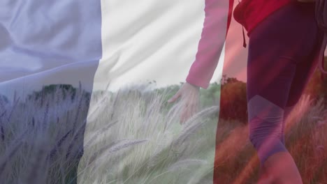 Animation-of-flag-of-france-over-happy-caucasian-woman-walking-at-field