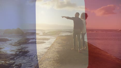 Animation-Der-Flagge-Frankreichs-über-Ein-Gemischtrassiges-Paar,-Das-Am-Strand-Spaziert