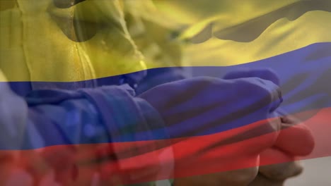 Animation-of-flag-of-colombia-over-biracial-male-soldier-holding-hands