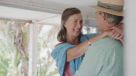 Happy-senior-caucasian-couple-embracing-in-wooden-beach-house,-in-slow-motion