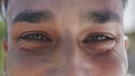 Portrait-close-up-of-eyes-of-happy-biracial-man-smiling-in-the-sun,-in-slow-motion