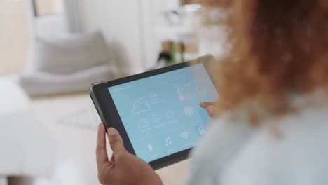 Biracial-Frau-Nutzt-Tablet-Mit-Smart-Home-Schnittstelle-Auf-Dem-Bildschirm-Im-Wohnzimmer,-Zeitlupe