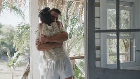 Happy-diverse-couple-embracing-on-sunny-beach-house-porch,-in-slow-motion