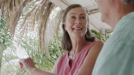 Happy-senior-caucasian-couple-smiling-and-embracing-on-porch-of-beach-house,-in-slow-motion