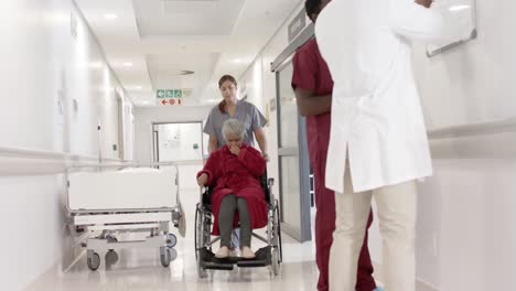 Diverse-female-nurse-walking-with-senior-patient-in-wheelchair-in-slow-motion,-unaltered