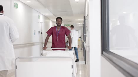 Serious-african-american-male-nurse-walking-with-hospital-bed-in-slow-motion,-unaltered