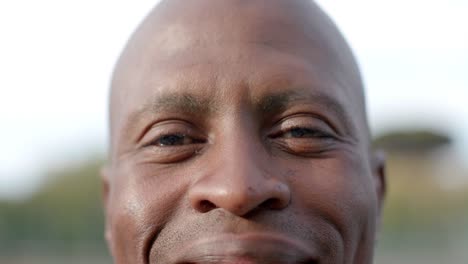 Portrait-close-up-of-happy-african-american-male-tennis-player-smiling-at-outdoor-court,-slow-motion