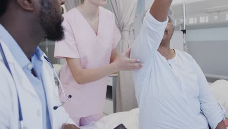 Diverse-male-doctor-with-tablet-and-female-physio-treating-happy-senior-female-patient,-slow-motion