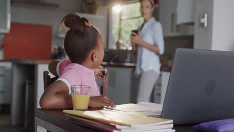 Happy-african-american-mother-and-daughter-using-laptop-and-doing-homework-together,-slow-motion