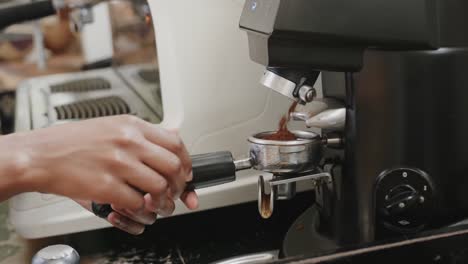 Close-up-of-african-american-female-barista-preparing-coffee-at-machine-in-coffee-shop,-slow-motion