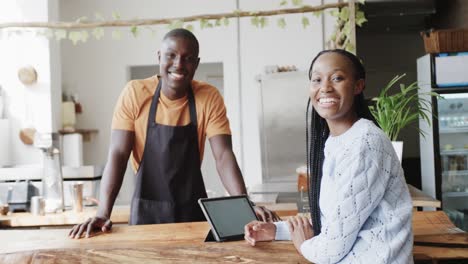 Portrait-of-happy-african-american-male-barista-and-female-customer-at-coffee-shop,-slow-motion