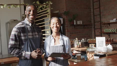 Portrait-of-smiling-african-american-female-and-male-coffee-shop-owners-at-work,-slow-motion