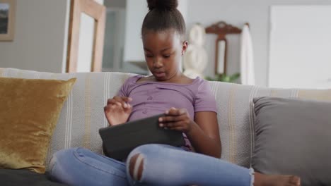 Chica-Afroamericana-Sentada-En-El-Sofá-Y-Usando-Tableta,-Cámara-Lenta