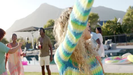 Happy-caucasian-woman-dancing-at-sunny-pool-party-with-diverse-friends,-slow-motion