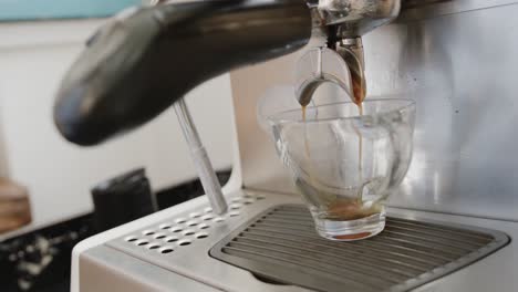 Close-up-of-coffee-pouring-into-cup-from-coffee-machine-at-coffee-shop,-slow-motion