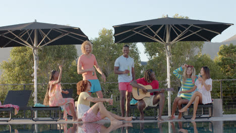 Happy-diverse-friends-with-drinks-talking-and-dancing-in-the-sun-at-pool-party,-slow-motion