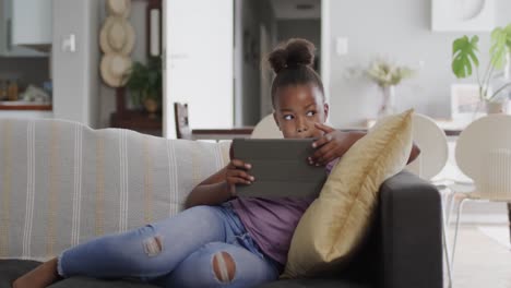 African-american-girl-sitting-on-sofa-and-using-tablet,-slow-motion