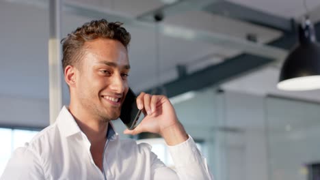 Happy-biracial-businessman-talking-on-smartphone-at-office,-in-slow-motion