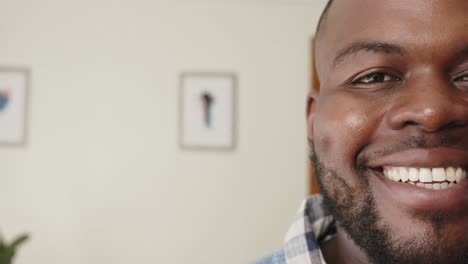 Half-portrait-of-happy-african-american-man-smiling-at-home,-with-copy-space,-in-slow-motion