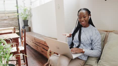 Fröhliche-Afroamerikanische-Frau,-Die-Einen-Laptop-Für-Videoanrufe-Benutzt-Und-Im-Café-Sitzt,-Zeitlupe