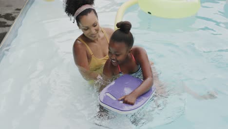 Glückliche-Afroamerikanische-Mutter-Und-Tochter-Spielen-Im-Schwimmbad-Im-Garten,-Zeitlupe