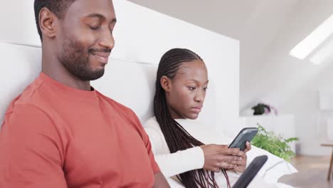 Afroamerikanisches-Paar-Sitzt-Im-Bett,-Beide-Benutzen-Smartphones,-In-Zeitlupe