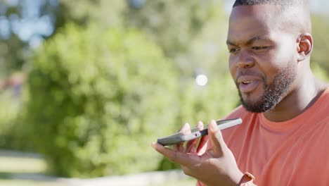 Glücklicher-Afroamerikanischer-Mann,-Der-Im-Sonnigen-Garten-In-Zeitlupe-Auf-Dem-Smartphone-Spricht