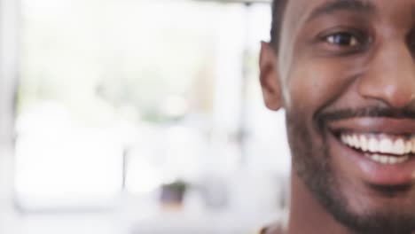 Half-portrait-of-happy-african-american-man-smiling-at-home,-in-slow-motion,-copy-space