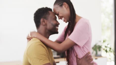 Happy-african-american-couple-smiling-and-embracing-in-living-room,-in-slow-motion