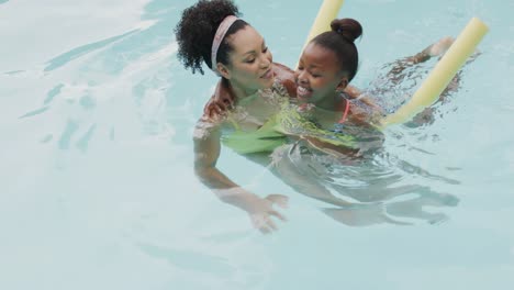 Happy-african-american-mother-and-daughter-playing-in-swimming-pool-in-garden,-slow-motion