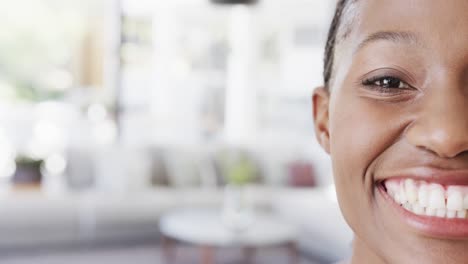 Half-portrait-of-happy-african-american-woman-smiling-at-home,-in-slow-motion,-copy-space