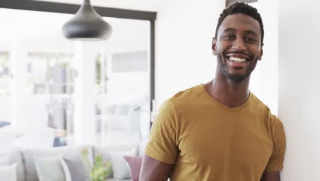 Portrait-of-happy-african-american-man-smiling-in-living-room-at-home,-in-slow-motion,-copy-space
