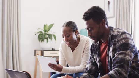 Glückliches-Afroamerikanisches-Paar-Benutzt-Laptop-Und-Diskutiert-Im-Wohnzimmer-über-Finanzen,-Zeitlupe