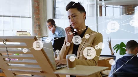 Animation-of-network-of-digital-icons-over-biracial-businesswoman-talking-on-smartphone-at-office