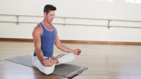 Hombre-Caucásico-Enfocado-Practicando-Meditación-De-Yoga-En-El-Gimnasio,-Cámara-Lenta