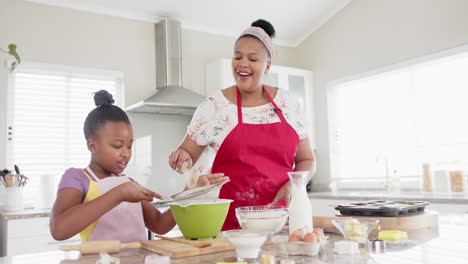 Happy-unaltered-african-american-mother-and-daughter-baking-in-kitchen,-in-slow-motion