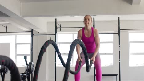 Focused-unaltered-caucasian-woman-exercising-with-battling-ropes-at-gym,-in-slow-motion