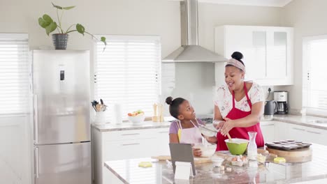 Happy-unaltered-african-american-mother-and-daughter-baking-in-kitchen,-in-slow-motion,-copy-space