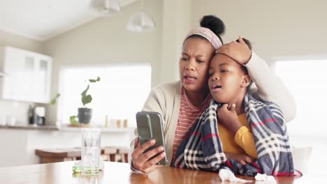 Madre-Afroamericana-Inalterada-E-Hija-Enferma-Usando-El-Teléfono-Para-Videollamadas-Médicas,-Cámara-Lenta